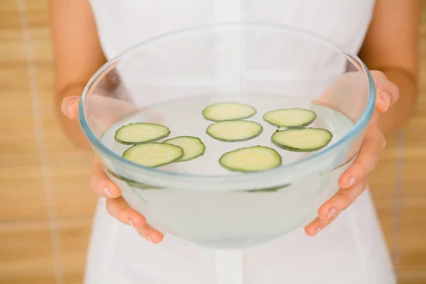 Woman holding bowl of water and cucumber — Stock Photo, Image