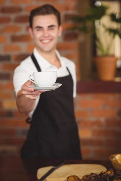 Lächelnder Barista bietet der Kamera eine Tasse Kaffee an — Stockfoto