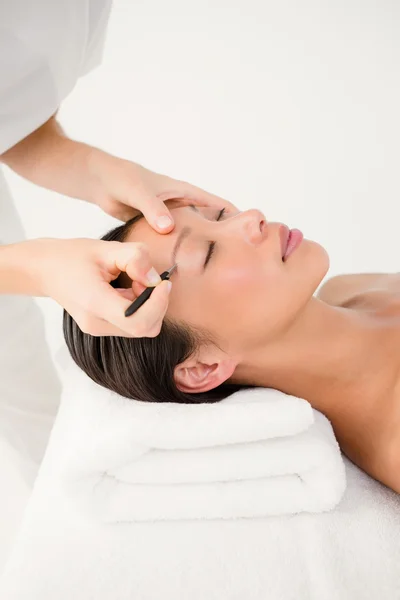 Woman using tweezers on patient eyebrow — Stock Photo, Image