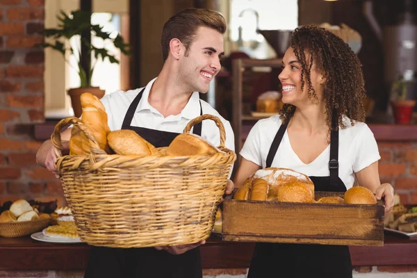 Glimlachend Ober en serveerster houden mand vol brood broodjes — Stockfoto