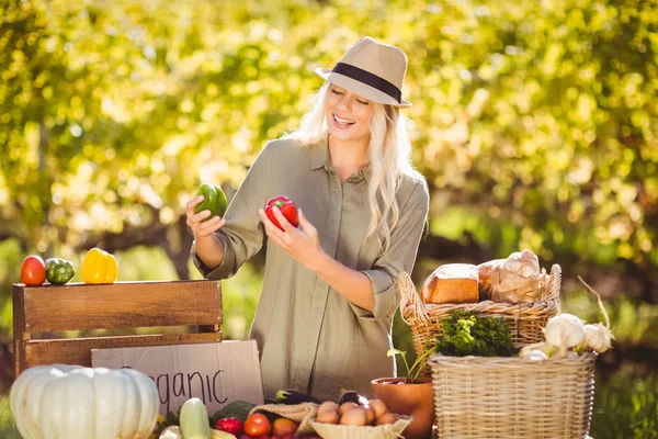 Lächelnde Blondine mit roten und grünen Paprika — Stockfoto