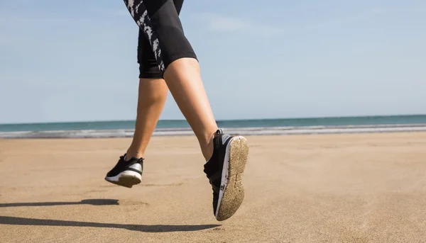 Vältränad kvinna jogging på sanden — Stockfoto