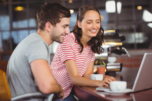 Amigos sonrientes usando el portátil y tomando café juntos —  Fotos de Stock