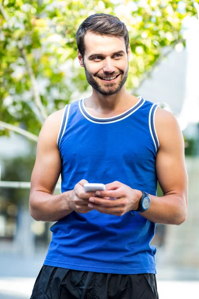 En stilig idrottsman med sin telefon — Stockfoto