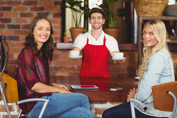 Leende kypare serverar kaffe till kunder — Stockfoto