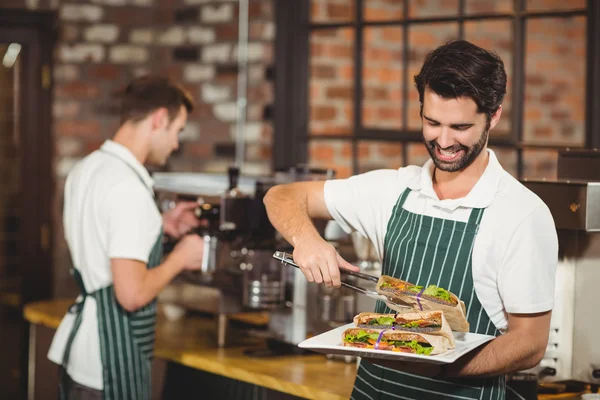 Leende servitör plocka en smörgås — Stockfoto