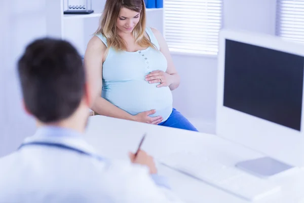 Arzt hört schwangerer Patientin zu — Stockfoto