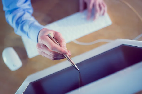 Businessman pointing to screen with pen — Stock Photo, Image