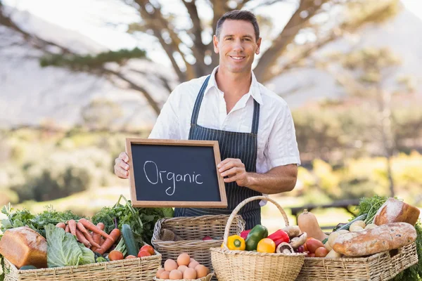 Smiling farmer holding an organic sign — Stock Photo, Image