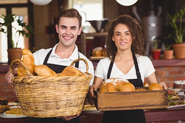 Glimlachend Ober en serveerster houden mand vol brood broodjes — Stockfoto