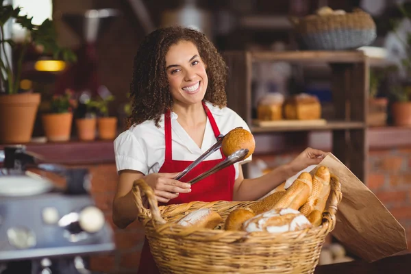 Serveerster oppakken van brood uit een mand glimlachen — Stockfoto