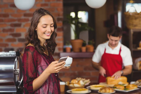 Hübsche Frau mit einer Tasse Kaffee und SMS — Stockfoto