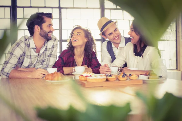 Amici che ridono gustando caffè e dolcetti — Foto Stock