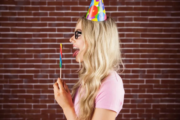 Hipster med party hatt hålla jätte lollipop — Stockfoto