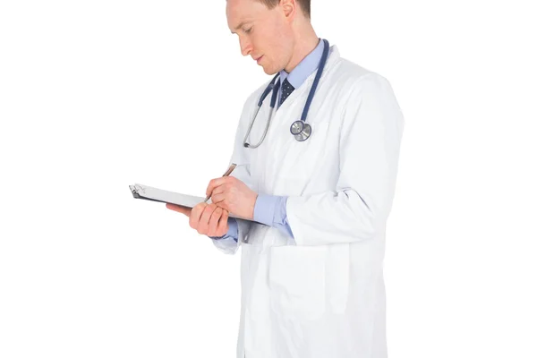 Médico serio escribiendo en un portapapeles — Foto de Stock