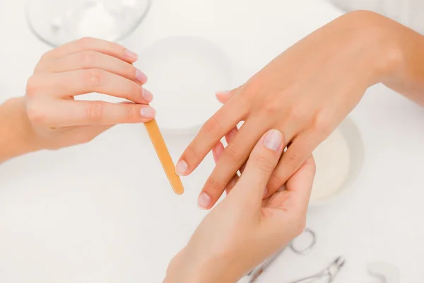 Kosmetolog arkivering kvinnliga klientens naglar — Stockfoto