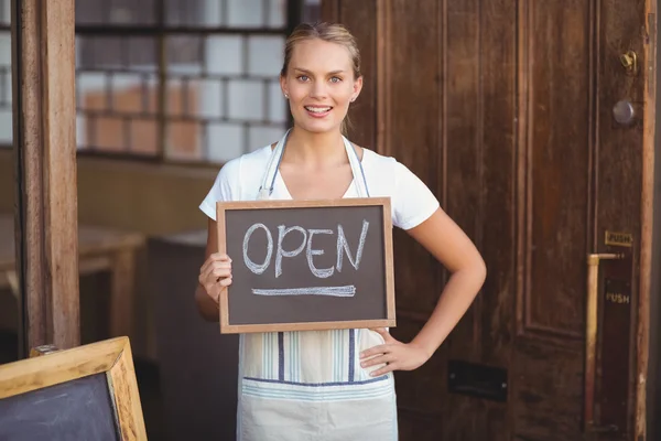 Lächelnde Kellnerin zeigt Tafel mit offenem Schild — Stockfoto