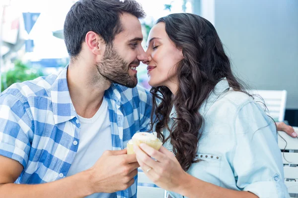 Par kyssas medan du håller cupcakes — Stockfoto