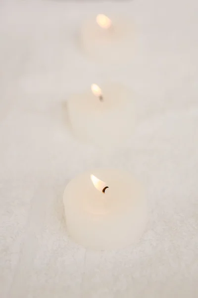 Três velas iluminadas em uma toalha — Fotografia de Stock
