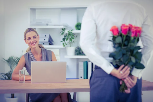 Man hiding bouquet in front of businesswoman — Stock Photo, Image