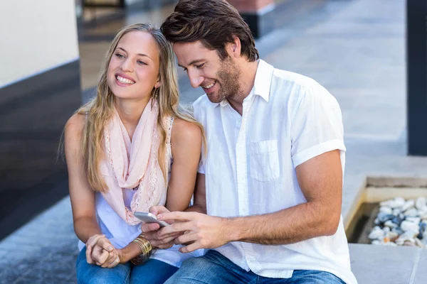 Pareja sentado y sosteniendo teléfono inteligente —  Fotos de Stock