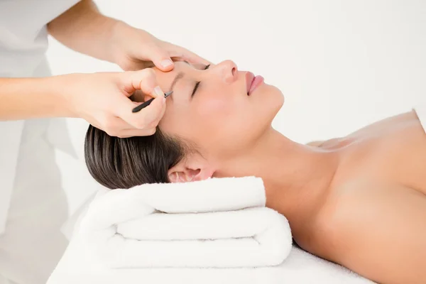 Woman using tweezers on patient eyebrow — Stock Photo, Image