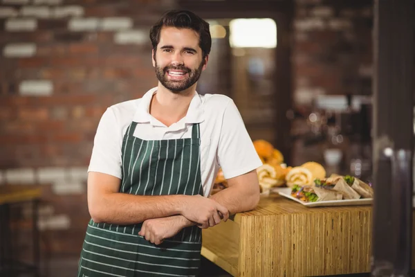 Barista sorridente inclinado no balcão — Fotografia de Stock