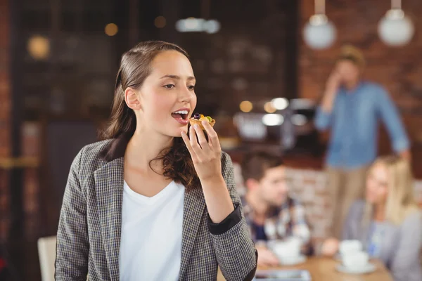 Usměvavá mladá žena jíst muffin — Stock fotografie