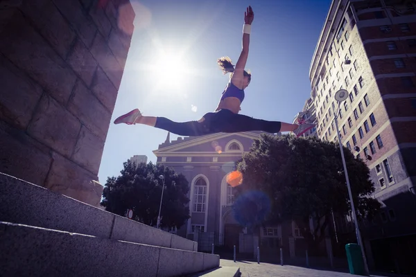 Athletic woman jumping off stairs — Stock Photo, Image