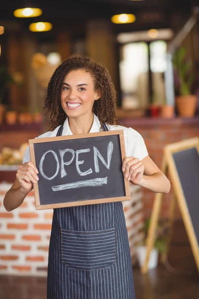 Smiling waitress showing chalkboard with open sign — Stock Photo, Image