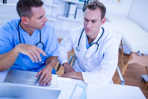 Colegas médicos concentrados discutiendo y trabajando con lapt —  Fotos de Stock