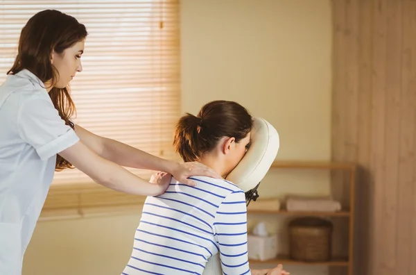 Young woman getting massage in chair — Stock Photo, Image