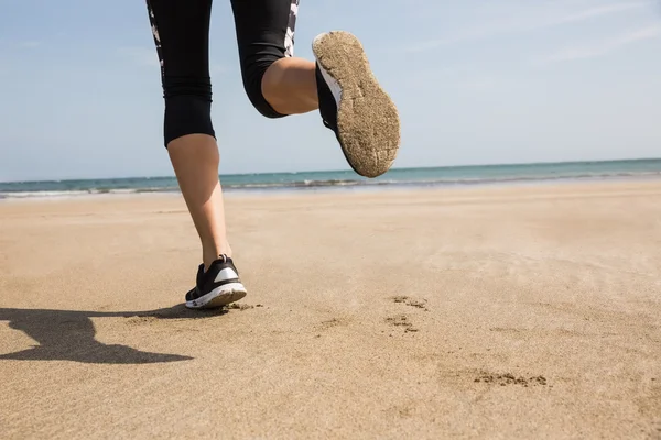 Vältränad kvinna jogging på sanden — Stockfoto