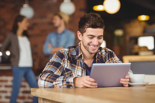 Un hipster souriant assis et utilisant une tablette — Photo