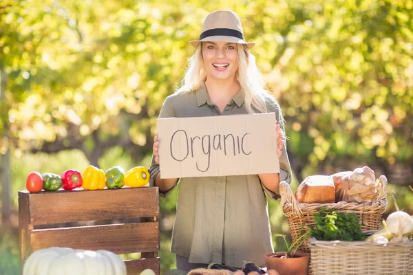 Usměvavá blondýnka drží organické vývěsní štít — Stock fotografie