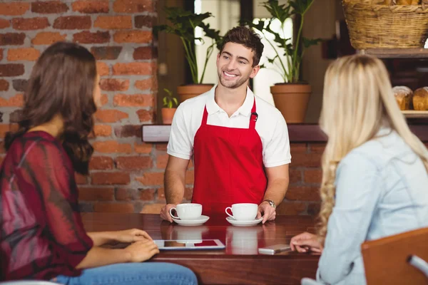 Leende kypare serverar kaffe till kunder — Stockfoto
