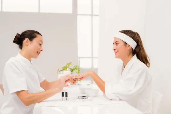 Beautician applying nail varnish to female nails — Stock Photo, Image