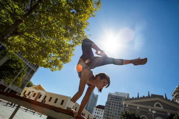 Mujer atlética realizando handstand en el banco —  Fotos de Stock