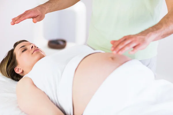 Mulher grávida relaxada recebendo tratamento reiki — Fotografia de Stock