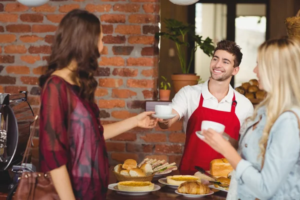 Lachende ober serveren een koffie aan een klant — Stockfoto