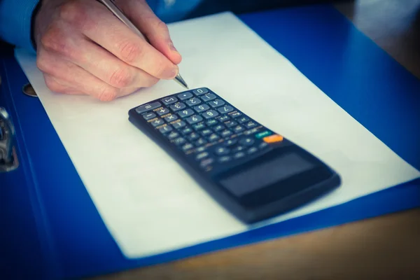 Businessman using a calculator and writing — Stock Photo, Image