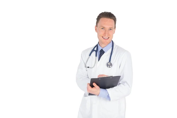 Médico sonriente escribiendo en un portapapeles — Foto de Stock