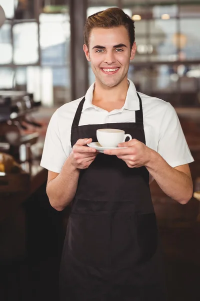 Улыбающийся бариста с чашкой кофе — стоковое фото