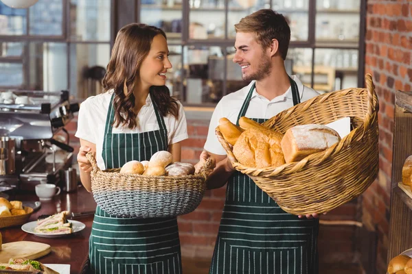 Colegas sorridentes segurando cesta de pães — Fotografia de Stock