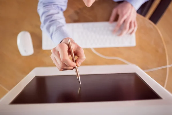 Businessman pointing to screen with pen — Stock Photo, Image