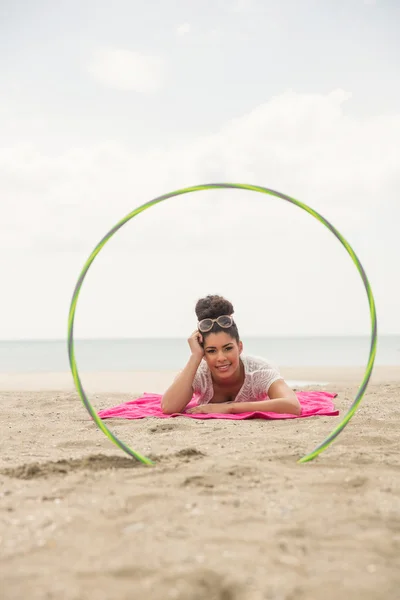 Sorrindo mulher olhando para a câmera através de hula hoop — Fotografia de Stock