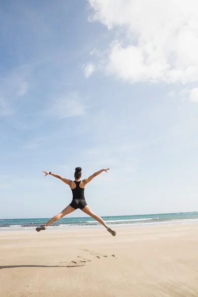 合适的女人在沙滩上跳跃 — 图库照片