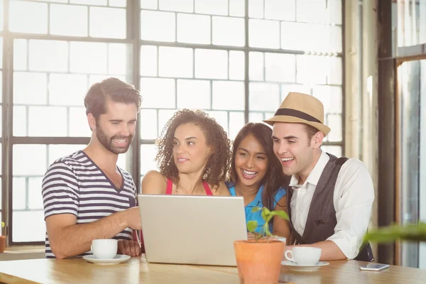 Amigos sorridentes olhando para o laptop e tomando café — Fotografia de Stock