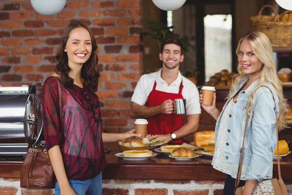Smiling waiter and two customers looking at the camera — Stock Photo, Image