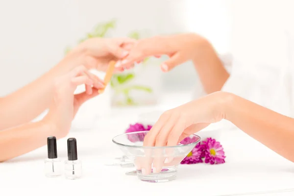 Beautician filing female client's nails — Stock Photo, Image